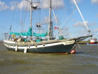 photo d'un voilier goelette en ferrociment à l'ancre sur une bouée. La goelette verte fait penser aux navires des livres d'histoire avec ses belles formes et son bout dehors qui semble partir en avant