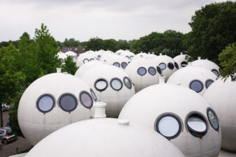 image présentant des sphères habitables, bolwoningen, il s'agit des maisons sphériques ou maisons boules, du créateur architecte néerlandais Dries Kreijkamp, elles semblent en file indienne, elles ont toutes des hublots ronds tournés vers le ciel, toutes blanches, c'est aux Pays-Bas, à Bois-le-Duc