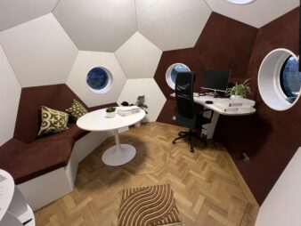 intérieur blanc et marron d'un conker avec bureau et coin salon avec une table ronde et canapé, et 3 hublots donnant sur l'extérieur