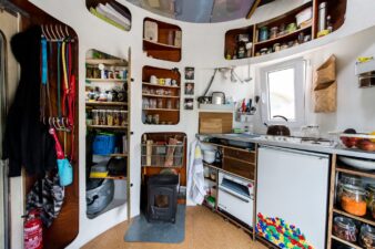 photo de l'intérieur de la cuisine de la mini maison silo à grains de Jan Korbes, le petit poêle à bois au centre, les ustensiles de cuisine, l'évier, la gazinière