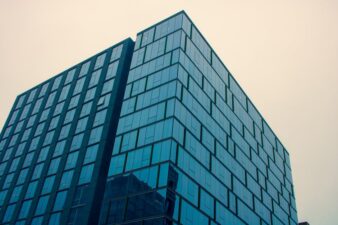 Contemporary glass building with blue reflections against an overcast sky.