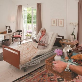 photo d'une dame senior seule dans sa chambre senior dans un ehpad, dans son lit médicalisé, avec ses meubles, allongée