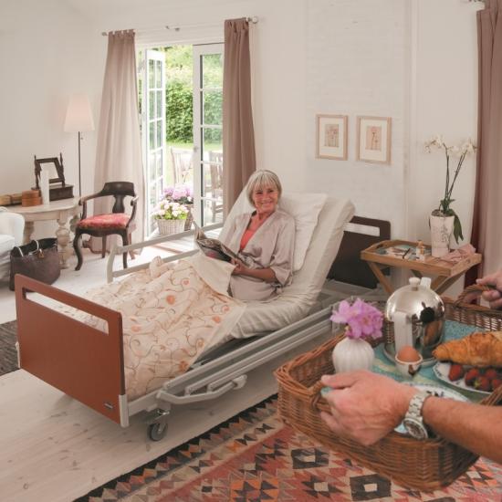 photo d'une dame senior seule dans sa chambre senior dans un ehpad, dans son lit médicalisé, avec ses meubles, allongée