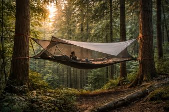 Tente-hamac suspendue entre plusieurs arbres dans une forêt avec une personne allongée à l’intérieur