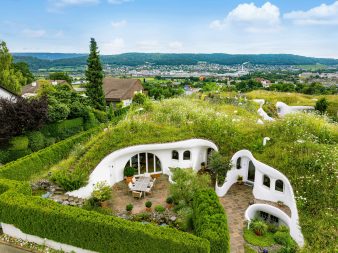 Maison organique avec toit végétalisé inspirée de Peter Vetsch intégrée dans le paysage naturel